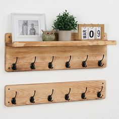 two wooden shelves with hooks on them and a potted plant in the corner next to it