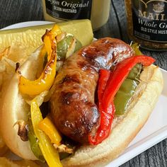 a hot dog on a bun with peppers and pickles next to some mustards