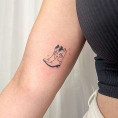 a woman's arm with a small tattoo of a boot and cat on it