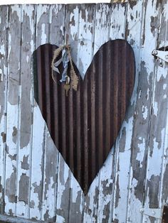 a heart shaped metal object hanging on a wooden fence