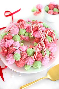 a white plate topped with pink and green cookies next to candy canes on top of a table