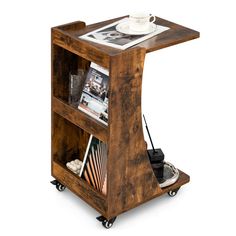 a small wooden shelf with magazines and other items on it's wheels, as well as a magazine rack