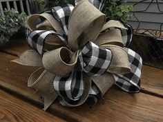 a large black and white bow sitting on top of a wooden table next to potted plants