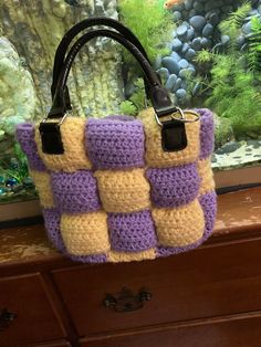 a crocheted handbag sitting on top of a dresser next to an aquarium