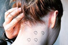 a woman's neck with three small tattoos on her left upper arm and behind the ear