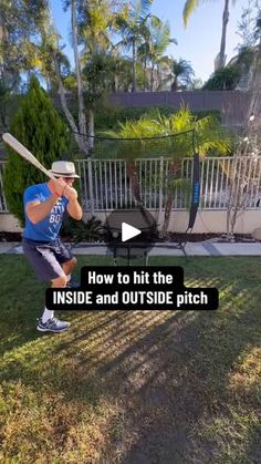 a man holding a baseball bat while standing on top of a lush green field in front of a white fence