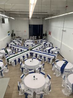 tables and chairs are set up in an empty room with white tablecloths on them