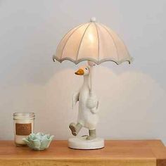 a white duck lamp sitting on top of a wooden table next to a glass jar