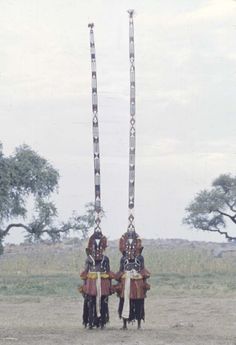 two men dressed in traditional african garb standing next to each other on the ground