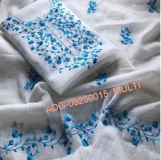 an embroidered white and blue cloth with flowers on it, sitting on top of a bed