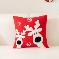 a red pillow with two reindeers on it