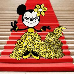 a cartoon mickey mouse standing on top of a red carpeted staircase with flowers in her hair