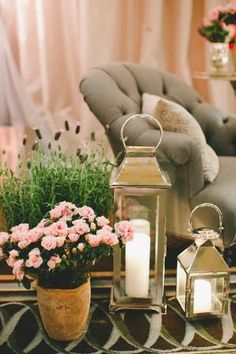 flowers and candles are sitting on a table in front of a couch with a chair