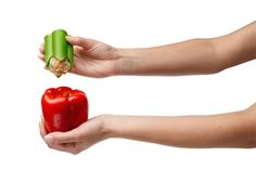 two hands holding an open pepper and a red pepper with a bite taken out of it