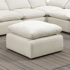 a large white couch sitting on top of a rug next to a footstool