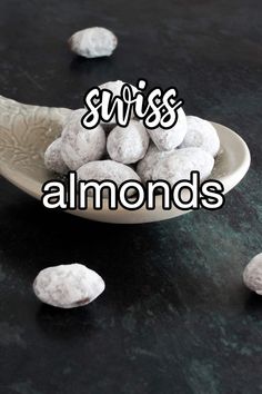 a spoon full of almonds sitting on top of a black table with the words swiss almonds above it