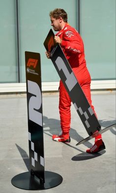 a man in red is holding his skis next to a pole with the number 25 on it