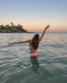 a woman standing in the water with her arms outstretched