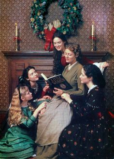 a group of women sitting next to each other in front of a christmas wreath on the wall