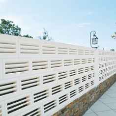 a white fence with some bricks on the side and a light hanging from it's side