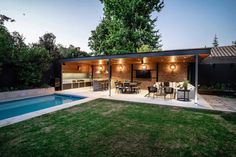 a backyard with a pool, patio and dining table next to the swimming pool is lit up at night