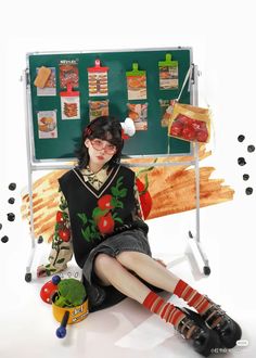 a woman sitting in front of a chalkboard with food on it's sides