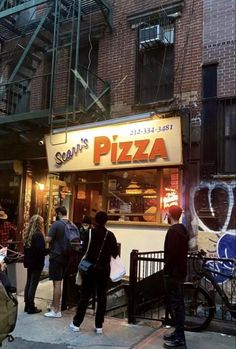 people standing in front of a pizza shop