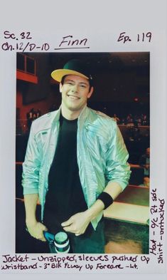 a man in a blue jacket and hat standing next to a white frame with the words on it