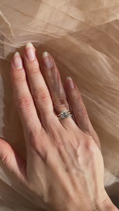 a woman's hand with a wedding ring on top of a veiled surface