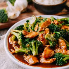 a white plate topped with broccoli and chicken covered in sauce on top of a table