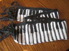 two black and white crocheted mitts sitting on top of a wooden table