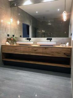 a bathroom with two sinks and a large mirror in the center, along with lights hanging from the ceiling