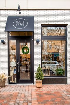 the front entrance to hand and land with potted plants on the sidewalk in front