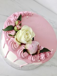 a cake with pink icing and white flowers on the top is sitting on a table