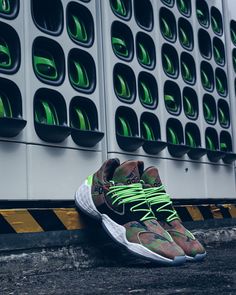 a pair of sneakers sitting on the ground next to a wall with green and white designs