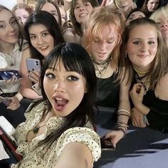 a group of young women sitting next to each other in front of a crowd of people