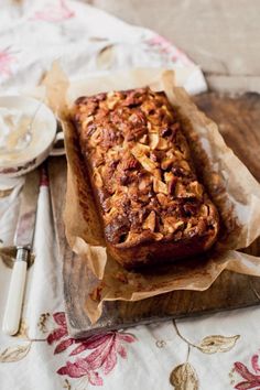 a loaf of bread sitting on top of a wooden cutting board next to a knife and fork