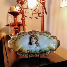 a decorative plate on a table with a lamp and other items in the room behind it