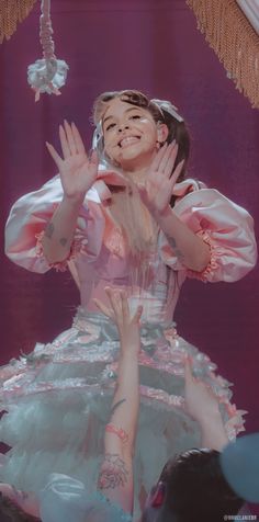 a woman with her hands up in the air while wearing a pink and white dress