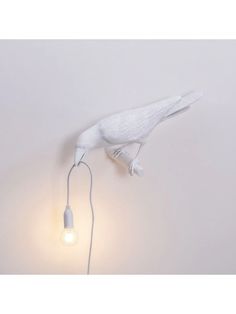 a white bird lamp on the wall next to a light bulb