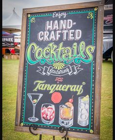 a chalkboard sign advertising hand crafted cocktails on the grass at an outdoor event