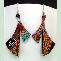 two colorful earrings hanging from a hook on a white wall with black and green accents