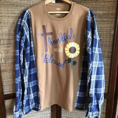 Upcycled oversized flannel tee, size L-2XL, light brown t-shirt with autumn sunflower graphic and words "Thankful and Blessed" combined with flannel sleeves of a light navy plaid fabric.  This reworked spliced shirt would make a great warm and comfy addition to your wardrobe this fall and winter! (WANT TO SEE MORE FROM THIS COLLECTION? Type RWTA in this store's search field.) These pieces are created to be an oversized fit. Please see measurements and approximate sizing below. DETAILS: APPROXIMATE SIZE:  L-2XL (depending on desired fit) Brands:  Sonoma Materials:  Cotton MEASUREMENTS: Top of shoulder to bottom hem:  28 inches Width across front at armpit:  30 inches This shirt is made from upcycled clothing, meaning previously owned/preloved.  Purchasing upcycled clothing is beneficial to Reworked Flannel, Sunflower Graphic, Upcycle Shirt, Oversized Flannel, Thankful And Blessed, Upcycled Clothing, Comfy Shirts, Hoodie Outfit, Blue Eye