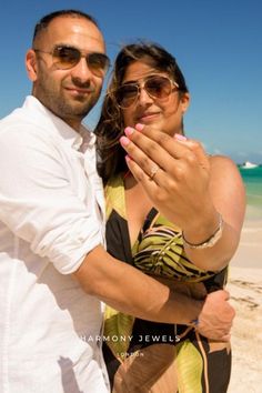 a man and woman pose for a photo on the beach