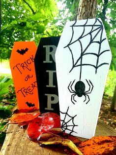 three halloween decorations are sitting on top of a wooden table in front of some trees