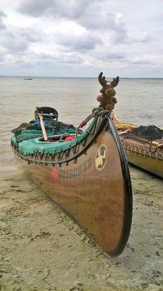 two canoes sitting on the beach next to each other