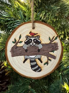 a wooden ornament with a raccoon on it hanging from a tree