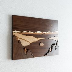 a wooden wall hanging with mountains on it