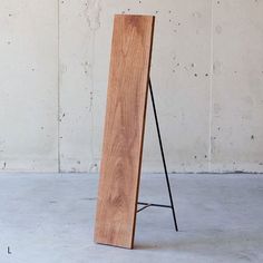 a large wooden object sitting on top of a cement floor next to a white wall