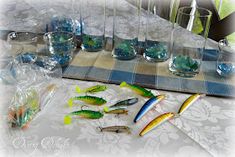 there are many different types of fishing lures on the table with cups and glasses